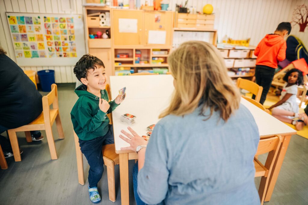 Kind spielt mit Erzieherin Uno