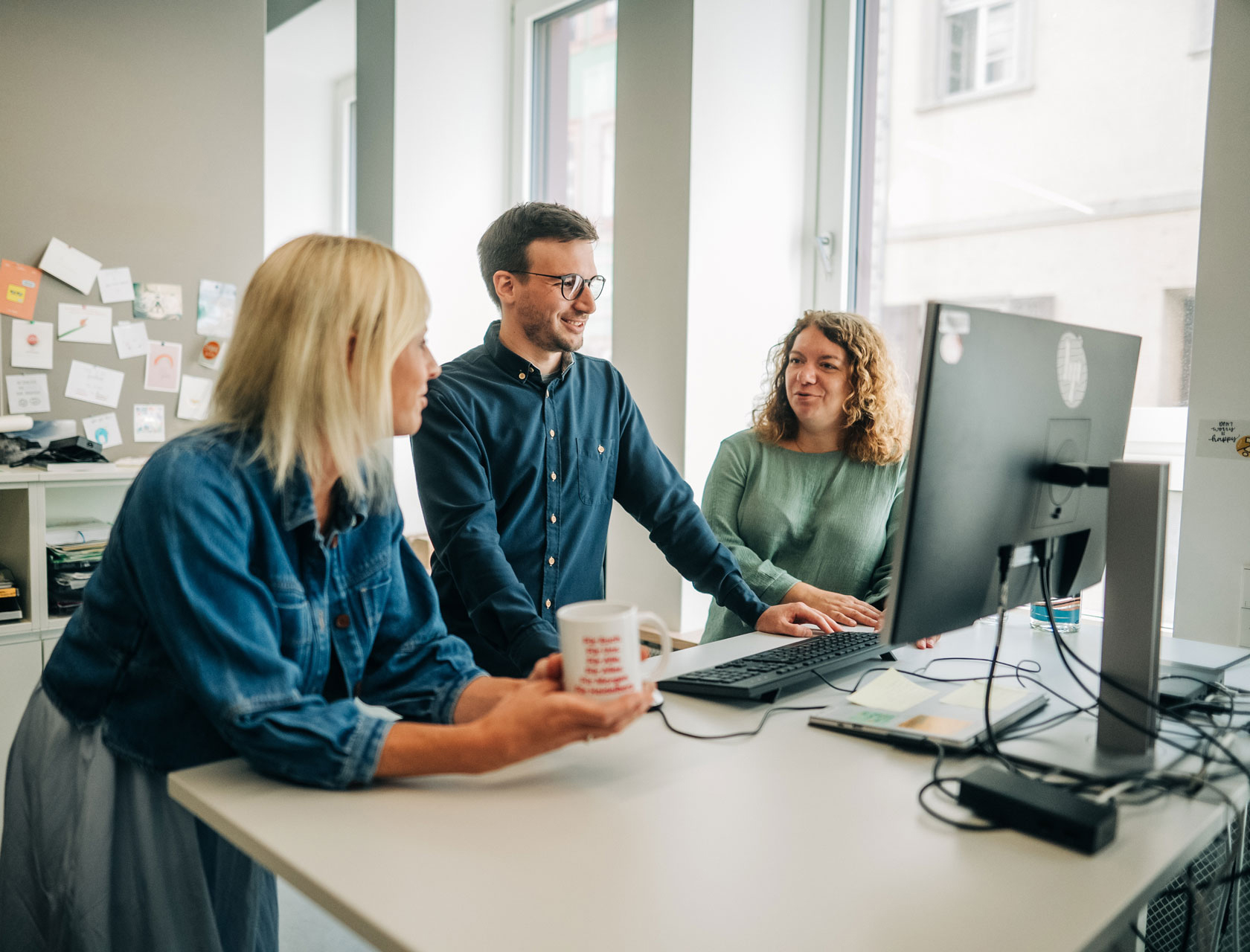 Drei Kollegen aus der Stadtverwaltung stehen gemeinsam vor einem Bildschirm.