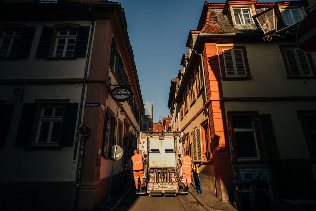 Müllwagen fährt mit zwei Müllmännern durch die Altstadt
