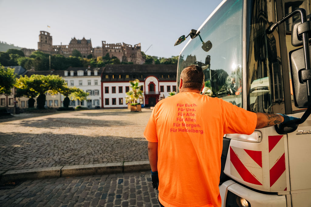 Swen Kautzner lehnt an das Müllauto und blickt aufs Heidelberger Schloss