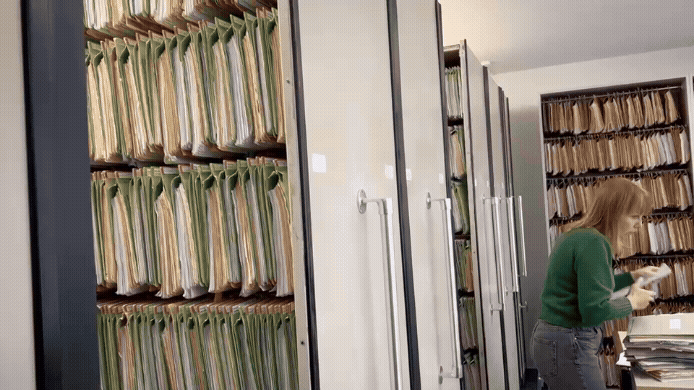 Mitarbeiterin in der Registratur sortiert Akten ein