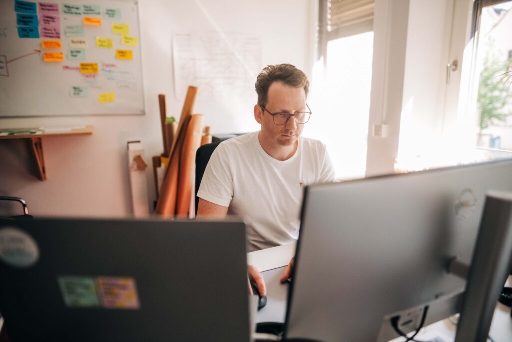 Mitarbeiter sitzt an seinem Arbeitsplatz mit Blick auf den Bildschirm