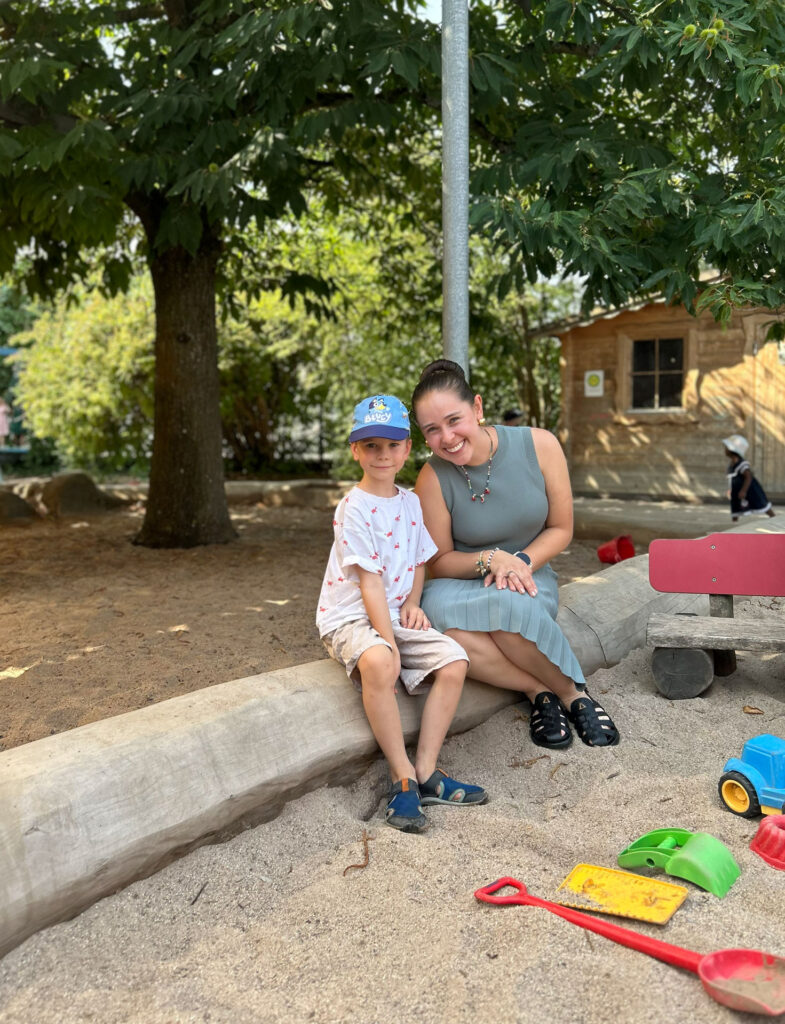 Andrea Gamboa mit einem Kind aus dem Kindergarten im Sandkasten