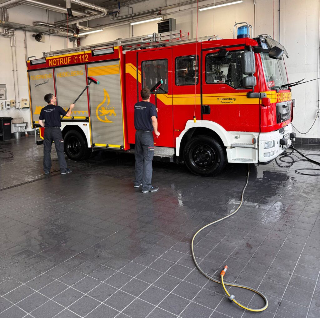 Zwei Auszubildende der Feuerwehr Heidelberg putzen ein Fahrzeug.