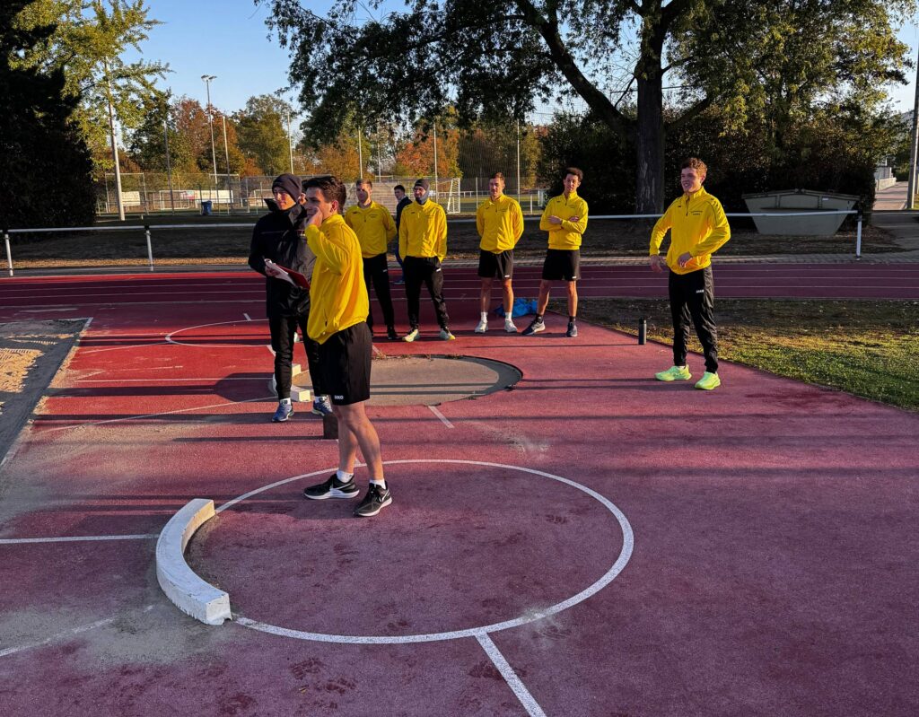 Die Auszubildenden üben Kugelstoßen während ihrer Sporteinheit